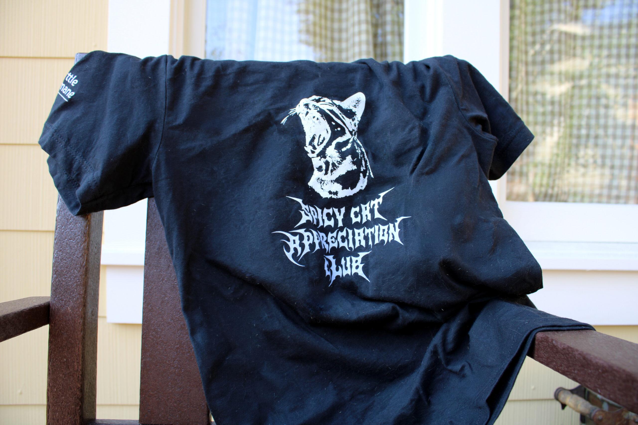 Spicy Cat Appreciation Club tee shirt lays on a chair