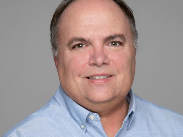 A man in a light blue polo looks at the camera